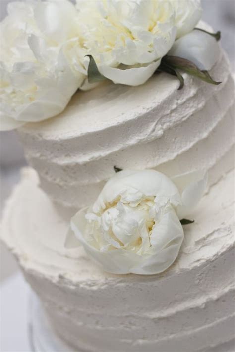 A Three Tiered Cake With White Flowers On Top