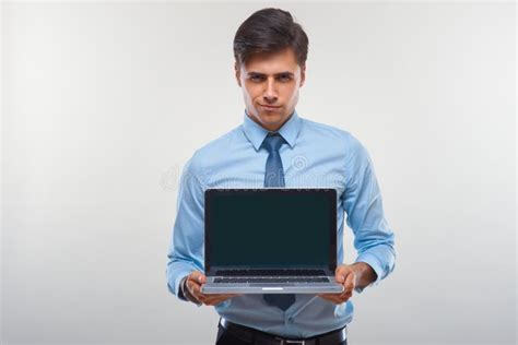 Business Man Holding A Laptop Against A White Background Stock Photo