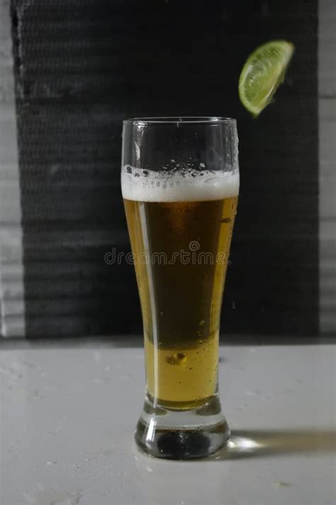 Tiro Vertical De Uma Lima Caiu Num Copo De Cerveja Foto De Stock