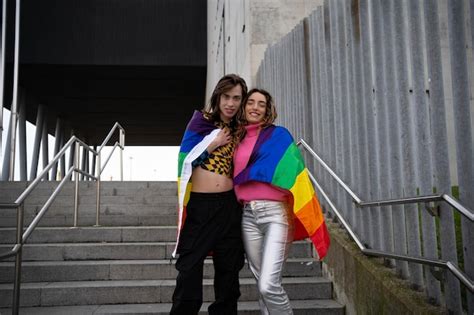 Mujer posando con un niño transgénero sonriente sosteniendo una bandera del orgullo gay Foto