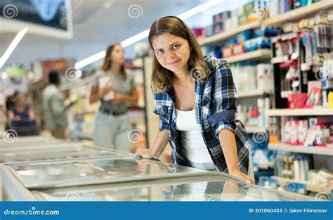 Woman Buyer Carefully Chooses Frozen Food In Store Freezer Stock Image