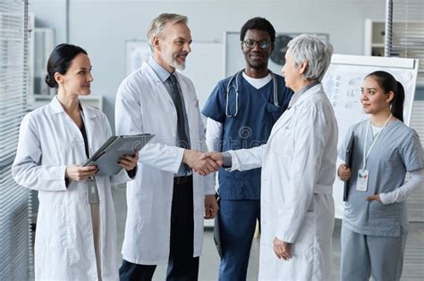 Mature Male General Practitioner Shaking Hand Of Experienced Female Colleague Stock Image