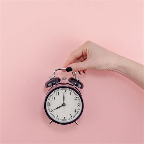 Premium Photo Cropped Hand Of Woman Holding Alarm Clock Against Pink