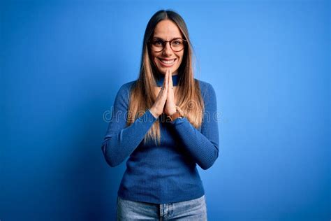 Jeune Belle Femme Blonde Aux Yeux Bleus Portant Des Lunettes Debout Sur Fond Bleu Prier Les