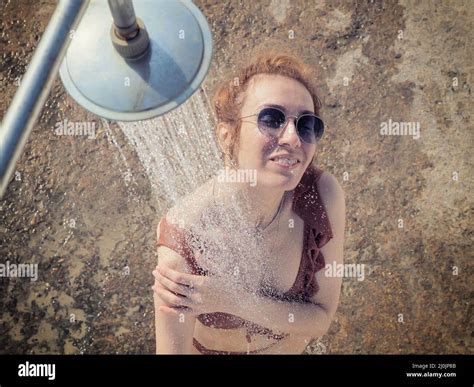 The Girl In Sunglasses And A Bikini Washes Under The Shower Outdoors