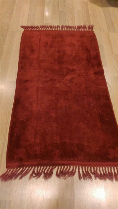 A Red Rug With Fringes On The Floor In Front Of A Wood Flooring Area