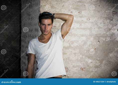 Handsome Young Man In Old Building Against Brick Wall Stock Photo