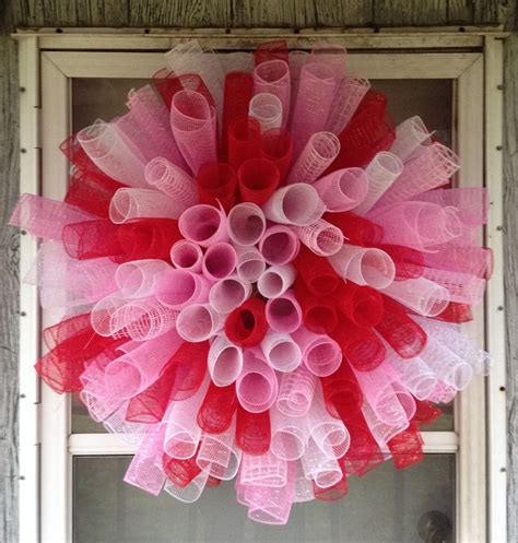 A Red And Pink Wreath Hanging On The Front Door To Decorate It For