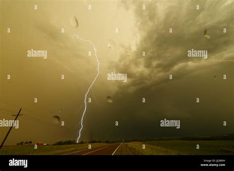 A Huge Bolt Of Lightning Strikes Near A Road During A Strong