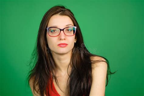 Studio Portrait Of Smart Brunette Woman In Eyeglasses And Red Shirt On Green Background Stock