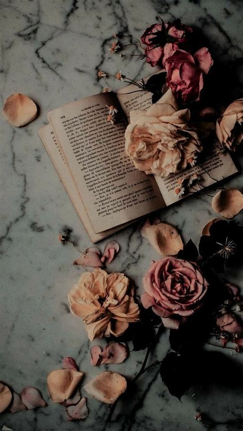 An Open Book Sitting On Top Of A Marble Table Next To Dried Flowers And