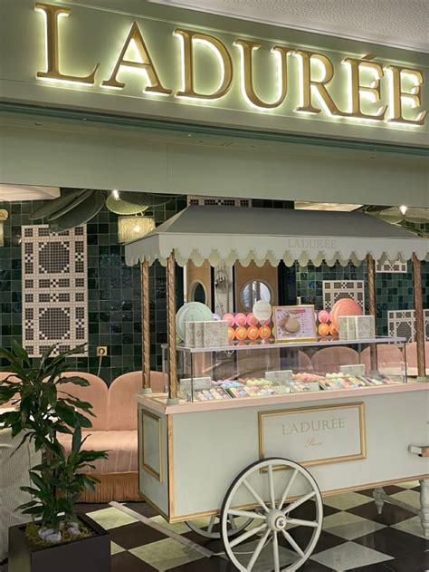 An Old Fashioned Ice Cream Cart Is In Front Of The Laduree Storefront