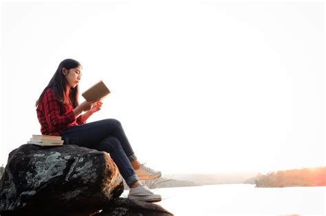 Premium Photo Side View Of Woman Reading Book While Sitting On Rock