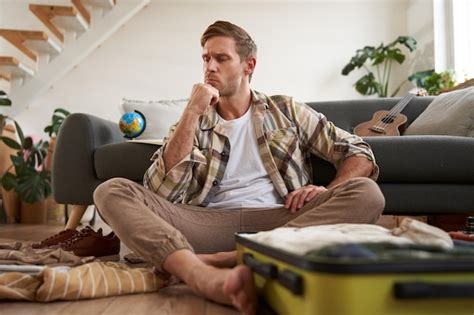 Retrato De Um Jovem Estressado Fazendo As Malas Decidindo Que Roupas