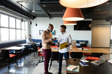 African American Businessmen Discussing Over File While Standing In