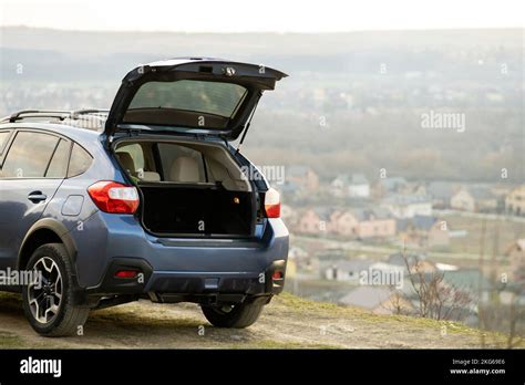 Blue Off Road Car With Open Trunk Lid At Dawn On Grassy Hill On Distant