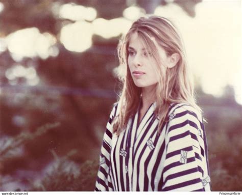 A Woman Standing In Front Of Trees With Her Hand On Her Hip And Looking Off To The Side