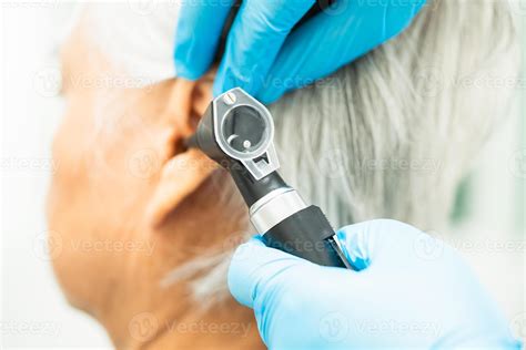 Audiologist Or Ent Doctor Use Otoscope Checking Ear Of Asian Senior