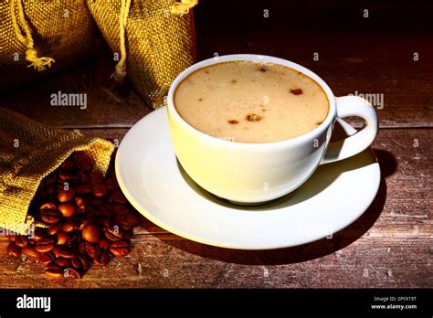 Coffee Cup Filled With Coffee With Sacks Of Raw Roasted Coffee Beans