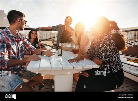 Groupe De Jeunes Gens Assis Autour D Une Table Avec Des Boissons Les Jeunes Hommes Et Femmes