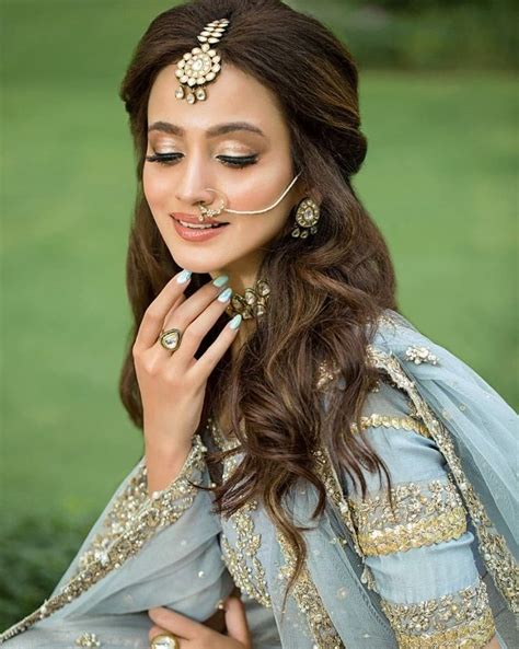 A Woman With Long Brown Hair Wearing A Blue Dress And Gold Jewelry On