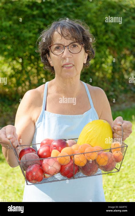 A Mature Woman With A Blue Dress And A Fruit Basket Stock Photo Alamy