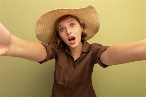 Impressionné jeune fille blonde portant un chapeau de plage s étendant les mains Photo Gratuite