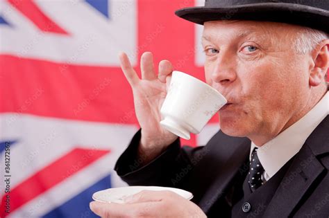 Englishman Drink Tea Wearing A Dark Suit With A Bowler Hat With A