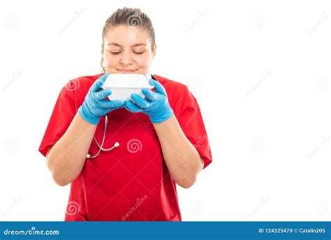 Young Medical Nurse Wearing Red Scrub Smelling Lunch Box Stock Image