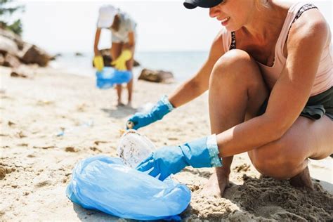 Mulher voluntária limpando a praia do mar coletando lixo em saco