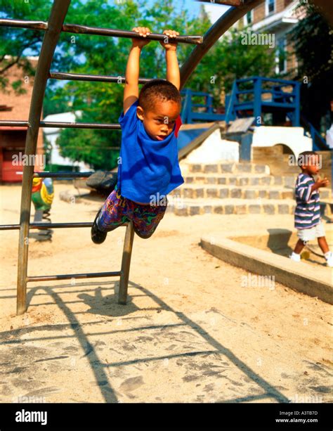 African American boy swinging on bar in the school playground Stock ...