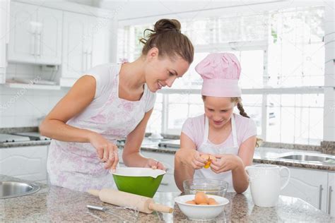 Girl Helping Her Mother Prepare Food In Kitchen Stock Photo By