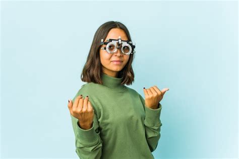 Jovem oculista latina sobre parede isolada apontando o dedo para você como se fosse um