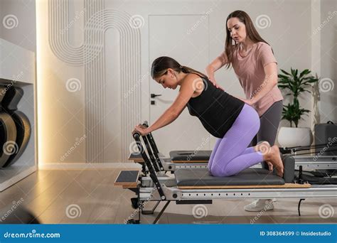 A Pregnant Woman Works Out On A Reformer Exercise Machine With A Personal Trainer Stock Image