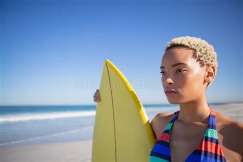 Beautiful Woman In Bikini Standing With Surfboard On Beach In The