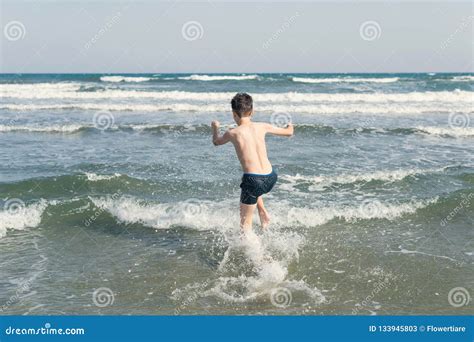 El Muchacho Que Salta En Ondas Del Mar Con Agua Salpica Concepto Imagen