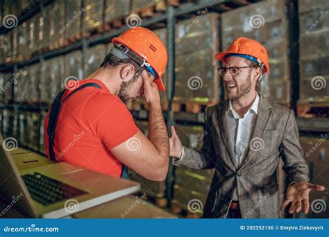 Manager Having A Conversation With The Warehouse Worker And Looking