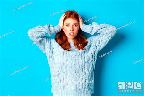 Nervous Redhead Girl Standing Overwhelmed Holding Hands On Head In Panic And Staring At Camera