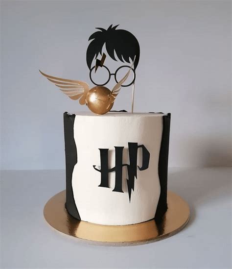 A Harry Potter Birthday Cake With Gold Accents And A Golden Bird Topper On Top