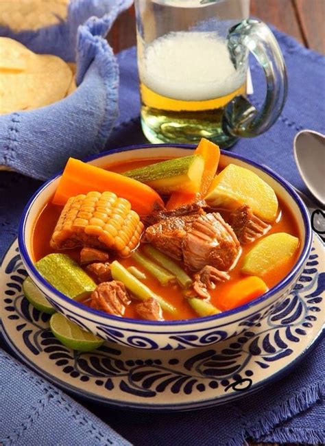 A Bowl Filled With Meat And Vegetables On Top Of A Blue Table Cloth