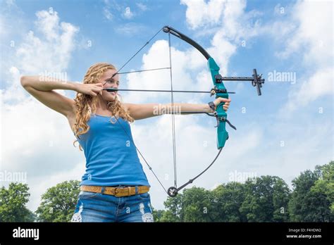 Blonde Caucasian Girl Shooting With Arrow And Compound Bow Outdoors On