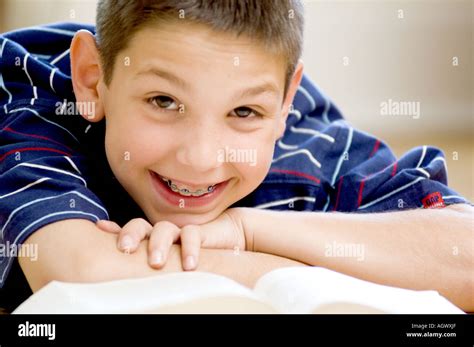 Smiling Boy With Braces Looking Up From Book Stock Photo Alamy