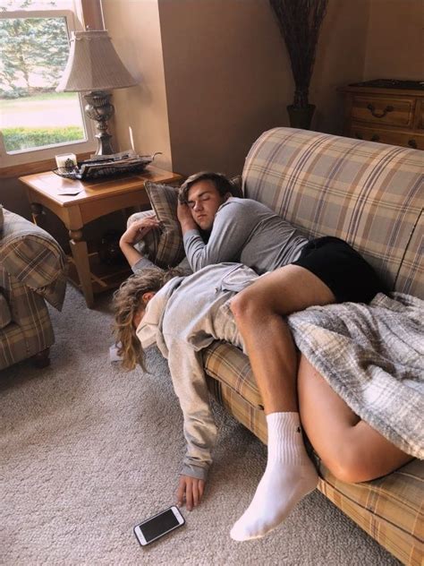 A Man And Woman Laying On A Couch In The Living Room With Their Cell Phones