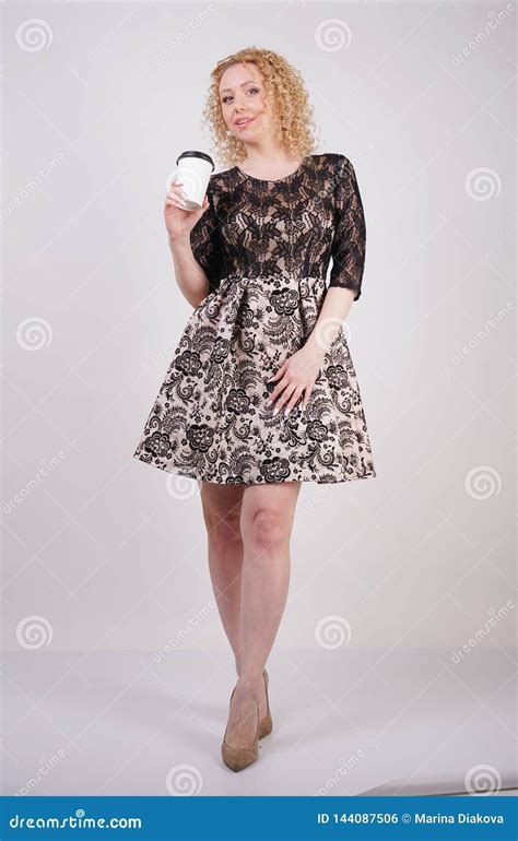 Cute Curly Blonde Girl Stands In Lace Short Evening Dress And Holds A