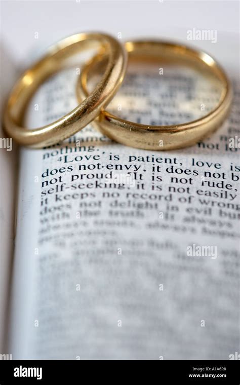 Two gold wedding rings lie on an open Bible. The verses are from 1 ...