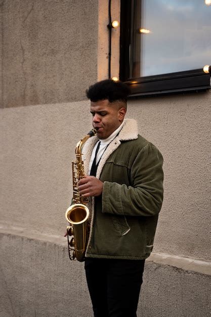 Homem de tiro médio tocando saxofone Foto Grátis