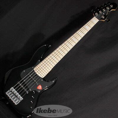 An Electric Bass Guitar Sitting On Top Of A Black Background