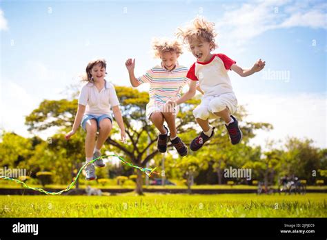 Happy Kids Play Outdoor Children Skipping Rope In Sunny Garden Summer