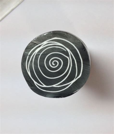 A Black And White Object With A Spiral Design On It S Surface Next To A