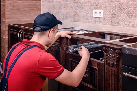 A Young Worker Installs A Drawer Installation Of Modern Wooden Kitchen